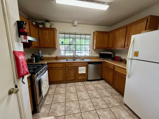 a kitchen with a sink a stove top oven a refrigerator and a window