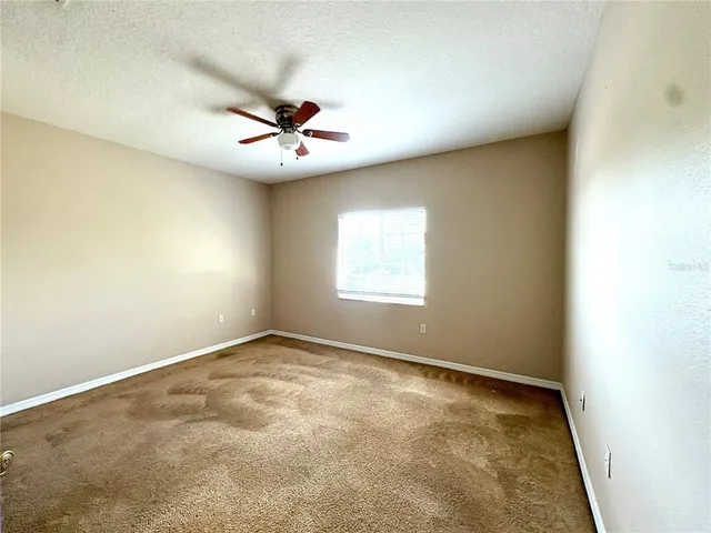 an empty room with a window and a fan