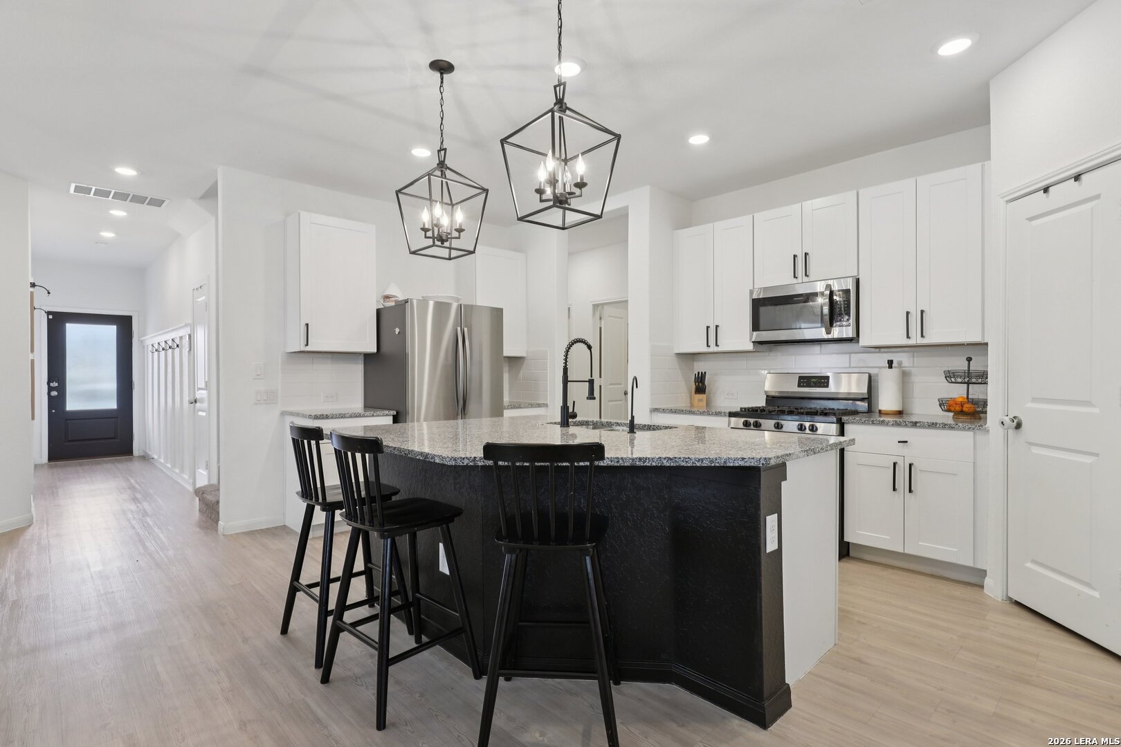 9062 Austin Seguin, TX 78155 - Photo 6 of 43 a kitchen with stainless steel appliances kitchen island granite countertop a dining table chairs and white cabinets