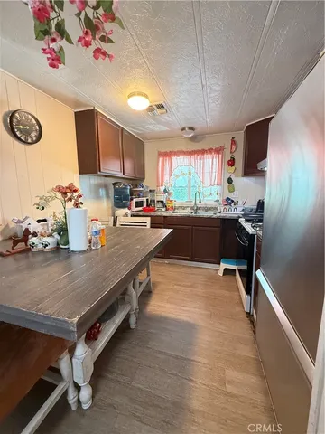 a kitchen with stainless steel appliances a refrigerator a stove a sink dishwasher with a dining table and chairs with wooden floor