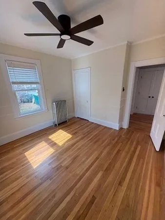 a view of empty room with wooden floor and fan