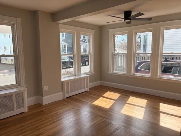 a view of empty room with wooden floor and fan