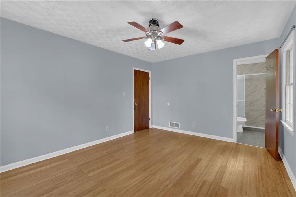 4341 Five Forks Trickum Road Southwest Lilburn, GA 30047 - Photo 14 of 35 a view of an empty room with wooden floor and a ceiling fan