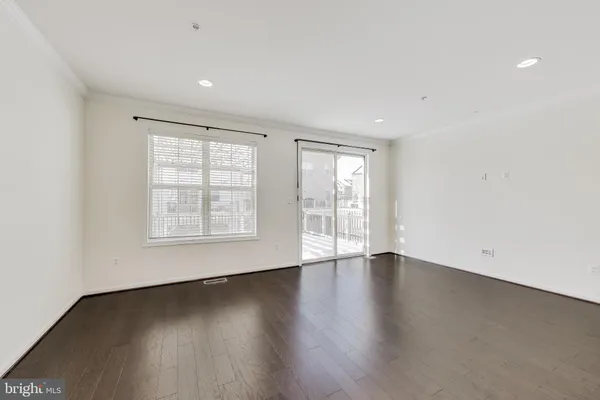 an empty room with wooden floor and windows with curtains