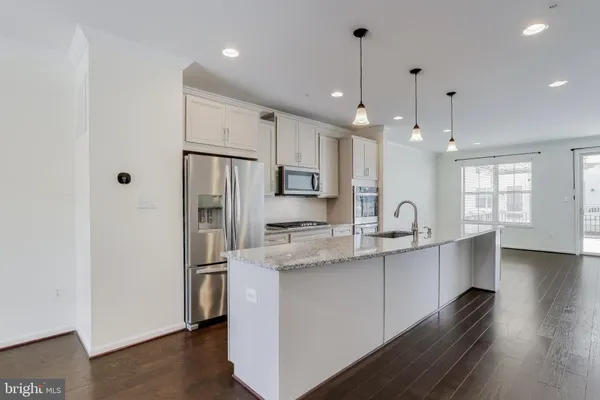 a kitchen with stainless steel appliances granite countertop a refrigerator a sink dishwasher a stove and white cabinets with wooden floor