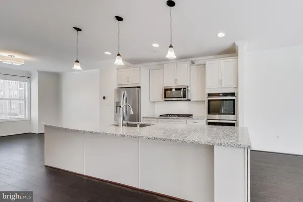 a kitchen with stainless steel appliances granite countertop a sink a refrigerator and a granite counter tops