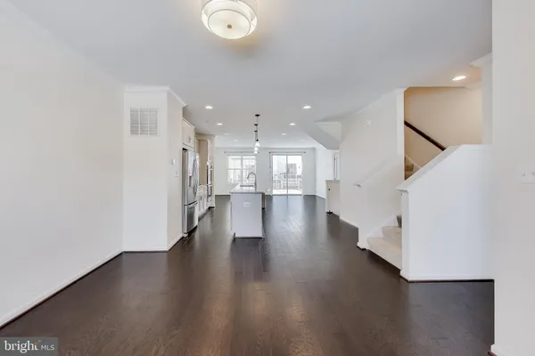a view of a hallway with wooden floor and a kitchen