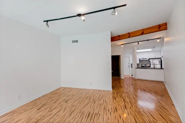 a view of a big room with wooden floor and a kitchen