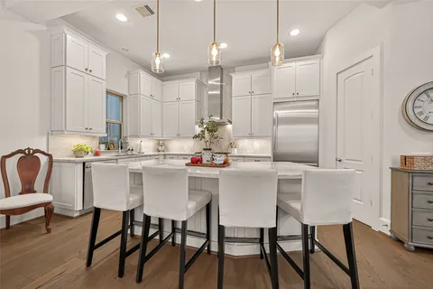 a kitchen with kitchen island a dining table chairs and white cabinets