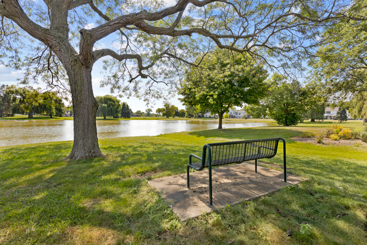 772 Leicester Road, Unit 772 Elk Grove Village, IL 60007 - Photo 18 of 21 a view of a lake with a bench and a yard