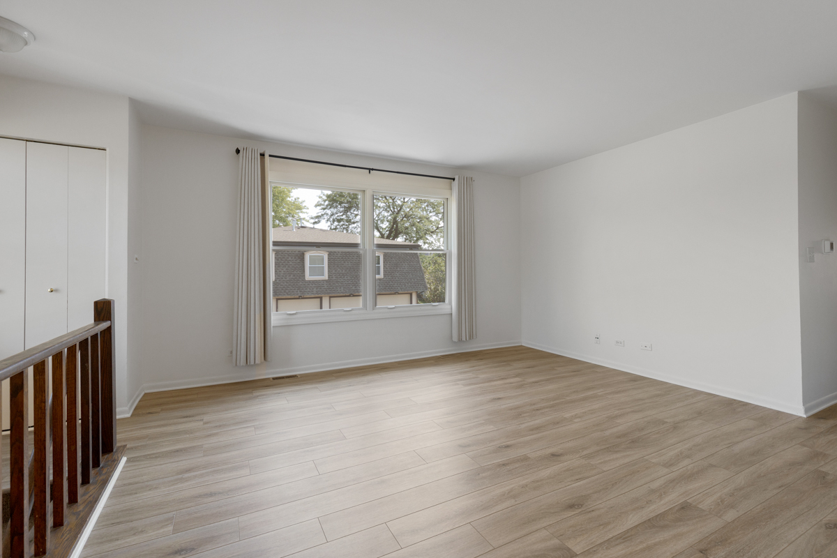 772 Leicester Road, Unit 772 Elk Grove Village, IL 60007 - Photo 3 of 21 a view of an empty room with wooden floor and a window