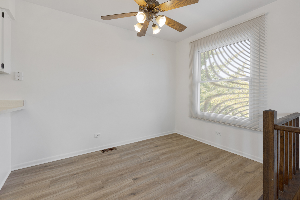 772 Leicester Road, Unit 772 Elk Grove Village, IL 60007 - Photo 5 of 21 an empty room with wooden floor fan and windows