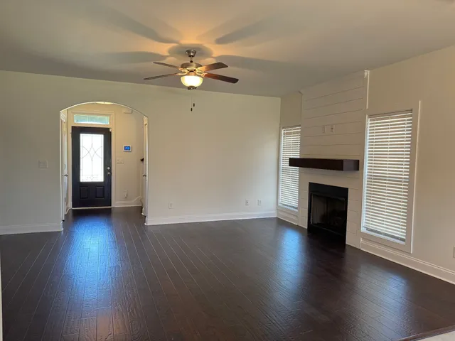 an empty room with wooden floor fireplace and windows
