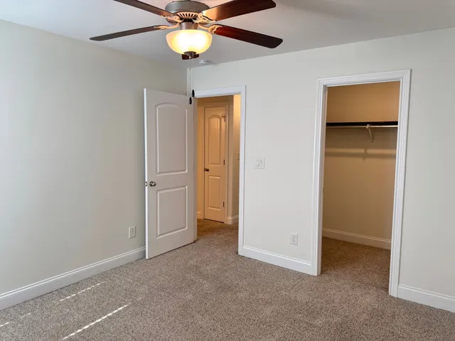 an empty room with closet and a chandelier fan