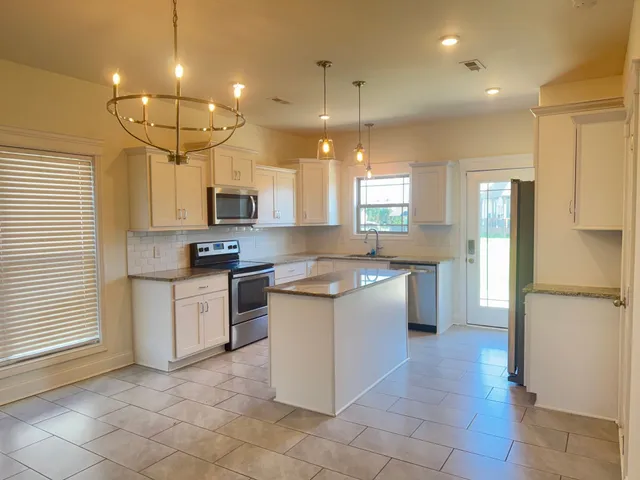 a large kitchen with a large counter top sink and refrigerator