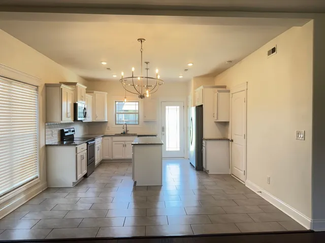 a view of an empty room with wooden floor and a ceiling fan