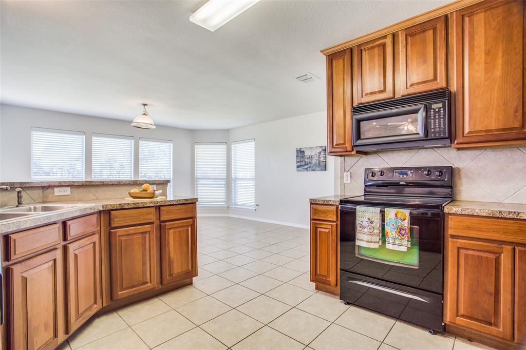 149 Shumard Drive Aledo, TX 76008 - Photo 5 of 12 a kitchen with stainless steel appliances granite countertop a stove a sink and a microwave