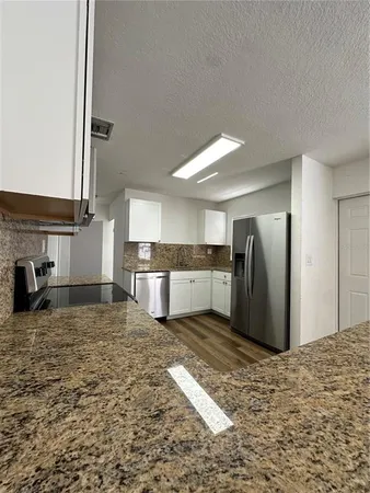 a view of a kitchen with kitchen island a sink wooden floor and a large window