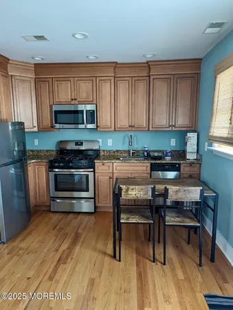 a kitchen with stainless steel appliances a stove a sink a microwave and wooden floors