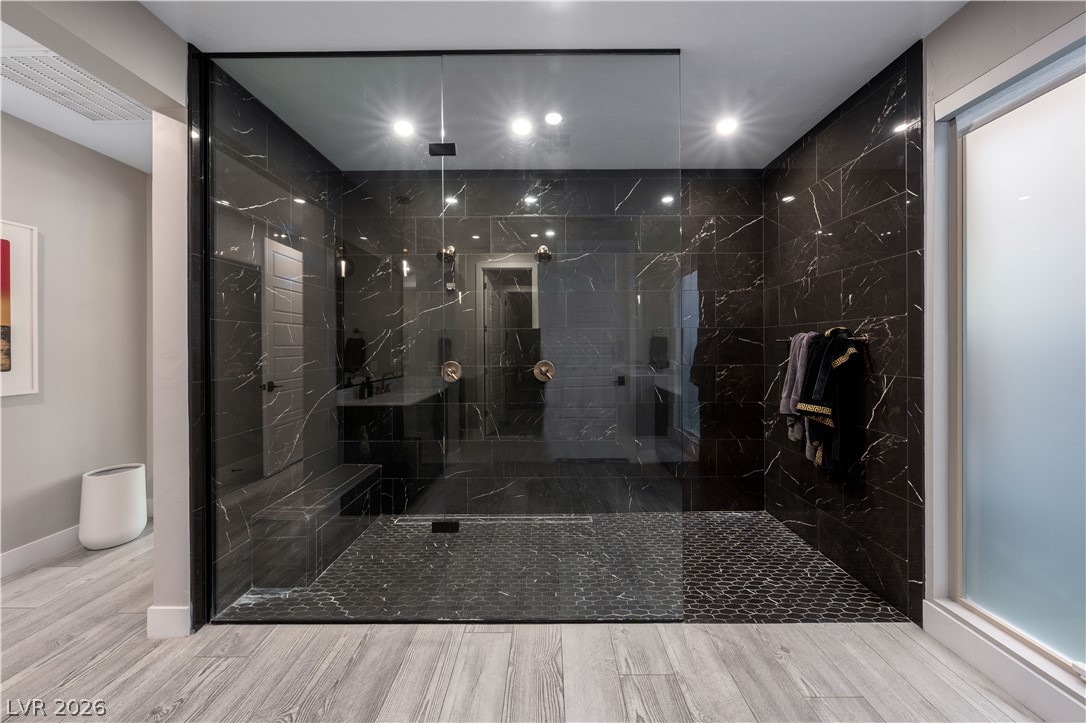 9719 Starlight Ridge Avenue Las Vegas, NV 89148 - Photo 13 of 25 A spacious, glass-enclosed walk-in shower features dark marble tile and dual shower fixtures.