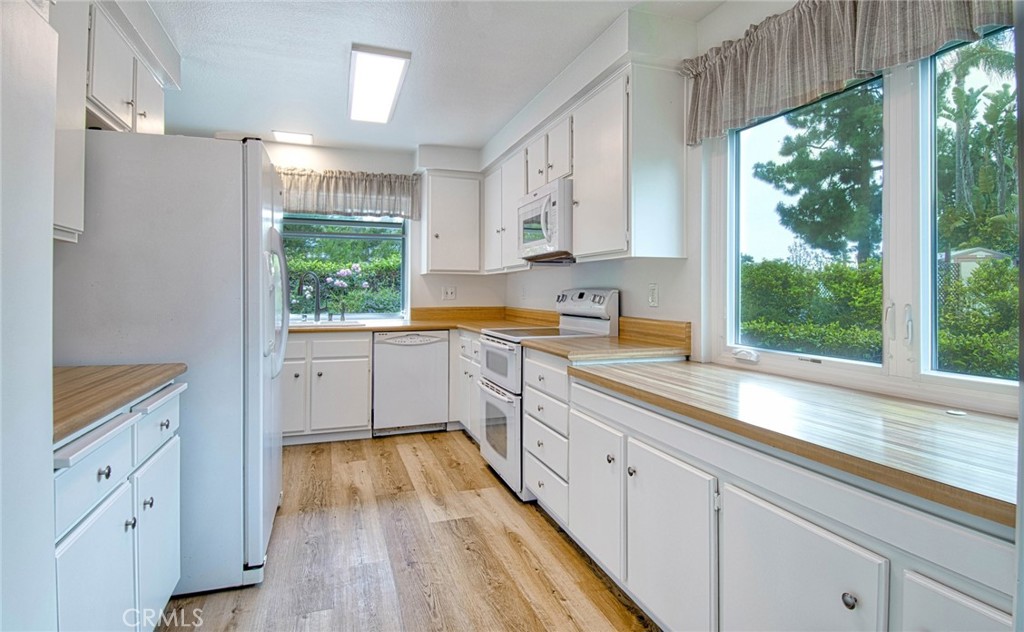 6061 Sierra Bravo Road Irvine, CA 92603 - Photo 8 of 22 a kitchen with white cabinets and wooden floors