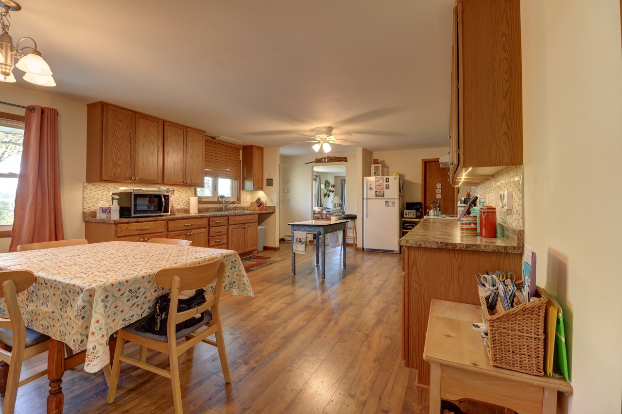 14755 Fenton Road Morrison, IL 61270 - Photo 7 of 34 a kitchen with stainless steel appliances granite countertop a stove top oven a sink a dining table and chairs with wooden floor