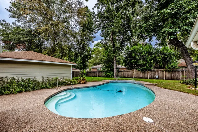 a view of a swimming pool with a yard and plants