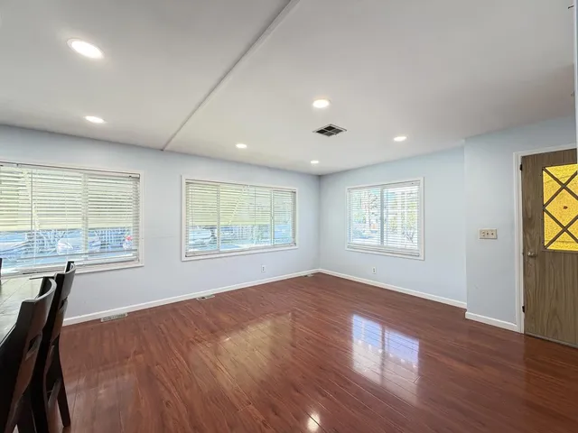 an empty room with windows and wooden floor