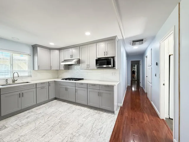 a large kitchen with cabinets wooden floor and stainless steel appliances