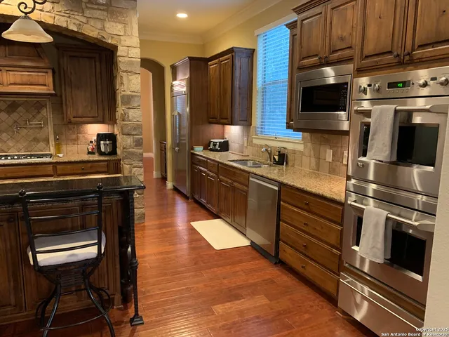 a kitchen with stainless steel appliances kitchen island granite countertop a stove a sink and a microwave