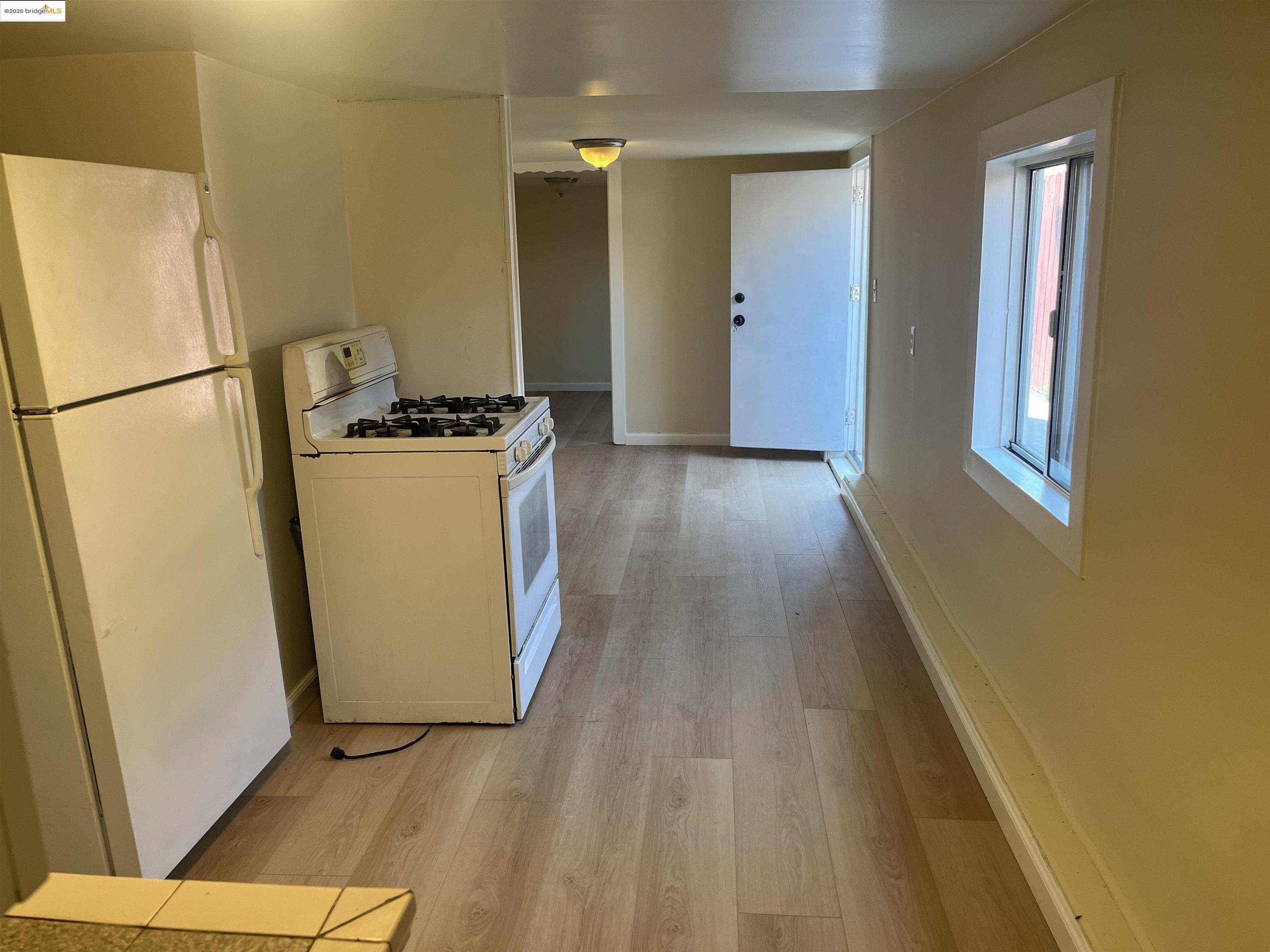 4114 East 17th Street Oakland, CA 94601 - Photo 18 of 39 a view of a kitchen with wooden floor and a refrigerator