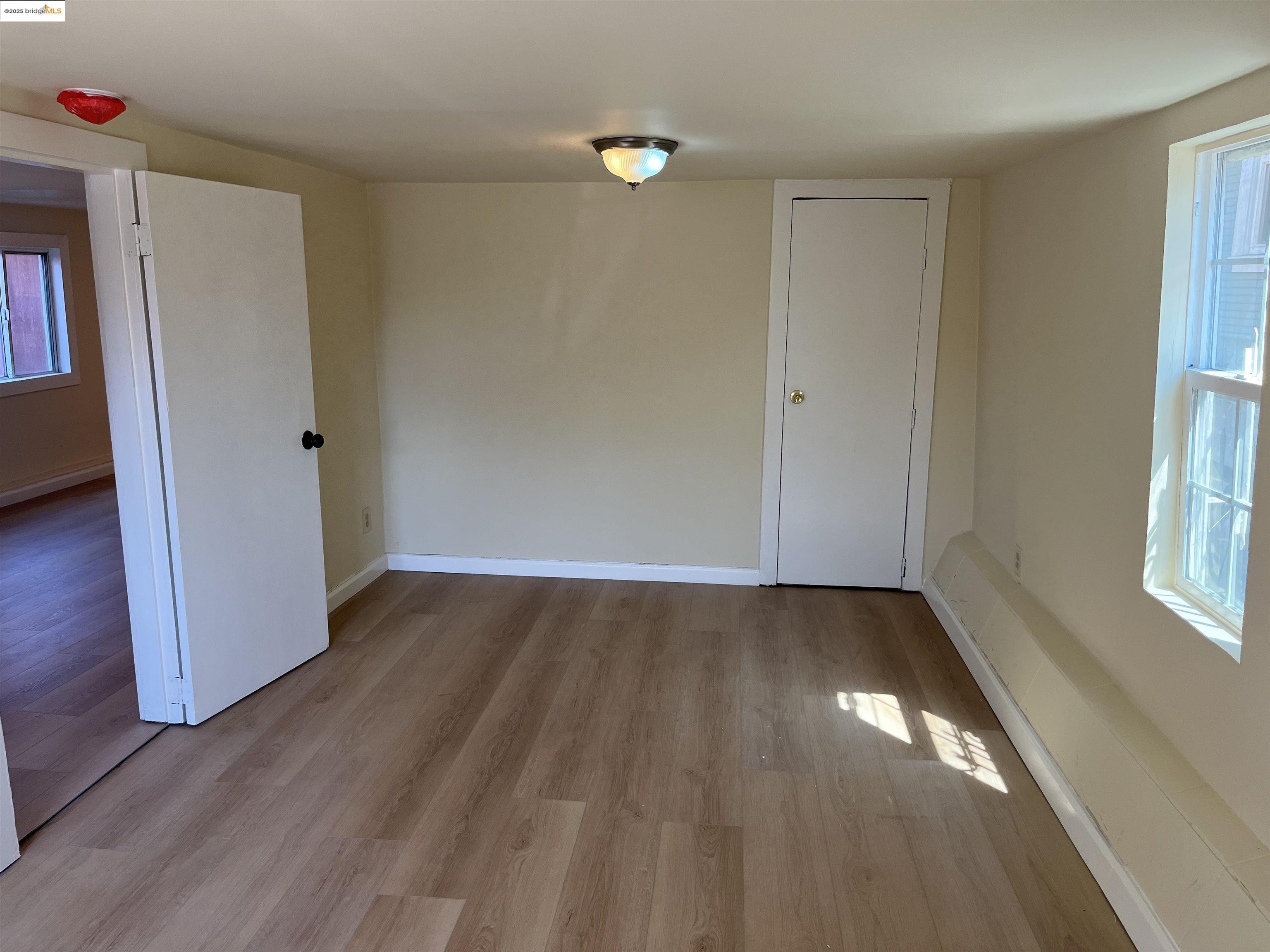 4114 East 17th Street Oakland, CA 94601 - Photo 21 of 39 an empty room with wooden floor and windows