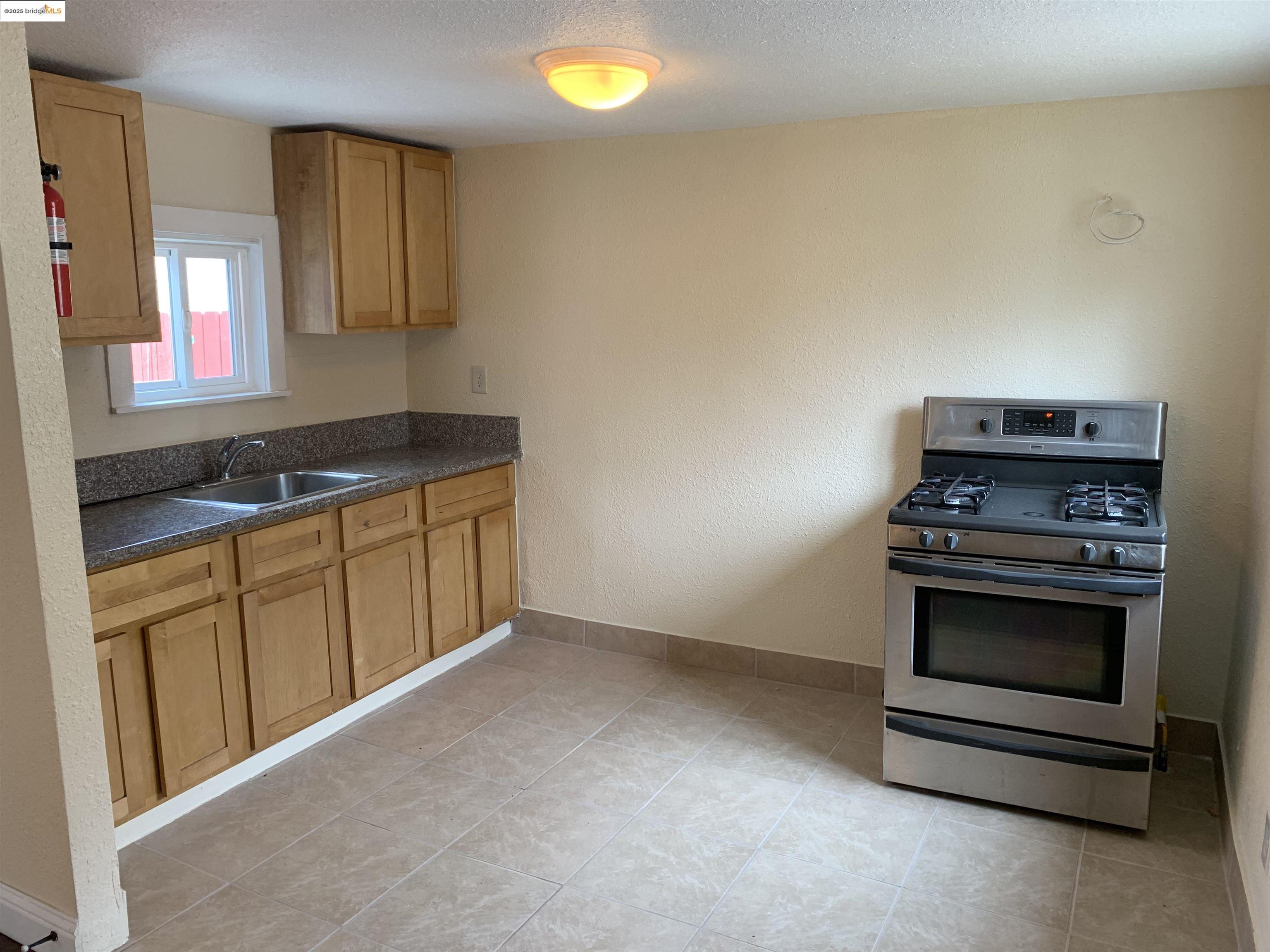 4114 East 17th Street Oakland, CA 94601 - Photo 29 of 39 a kitchen with granite countertop a stove a sink and a microwave