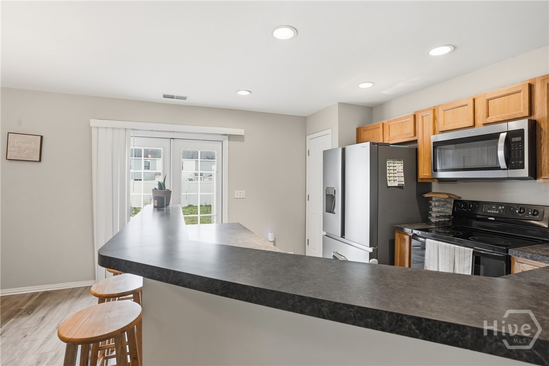 61 Timber Crest Court Savannah, GA 31407 - Photo 8 of 29 Open kitchen with breakfast bar seating, wood cabinets, standard appliances, recessed lighting, and sliding glass doors leading to the backyard