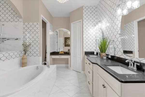 a spacious bathroom with a granite countertop double vanity sink a mirror a bathtub and shower