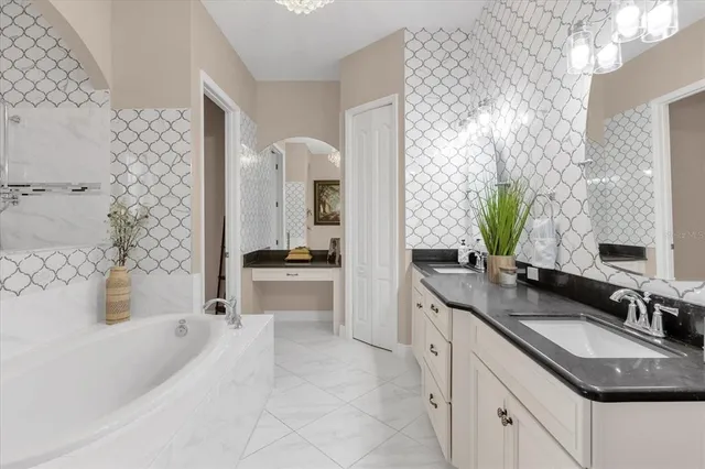 a spacious bathroom with a granite countertop double vanity sink a mirror a bathtub and shower