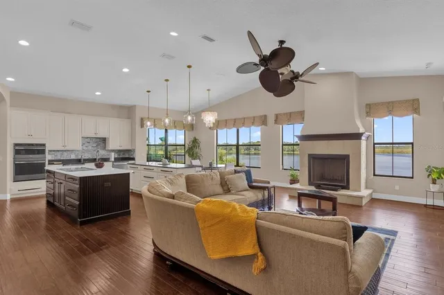 a living room with couches kitchen view and a fireplace