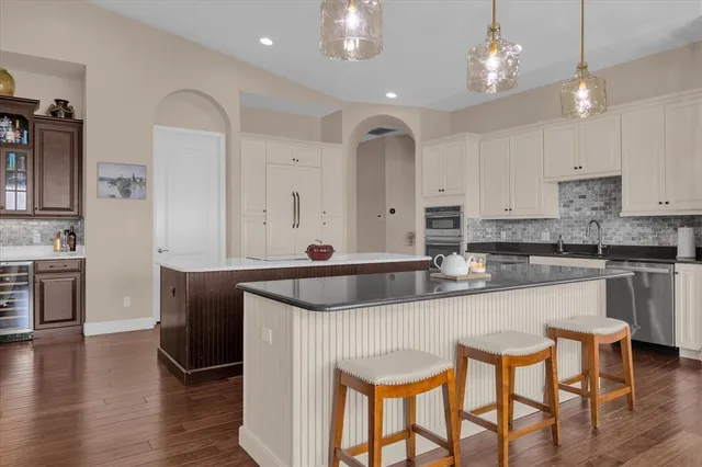 a kitchen with stainless steel appliances granite countertop a kitchen island and chairs in it