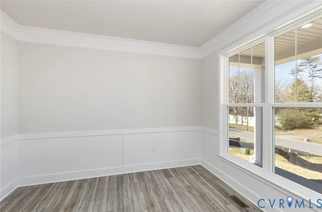 a view of an empty room with a window and wooden floor