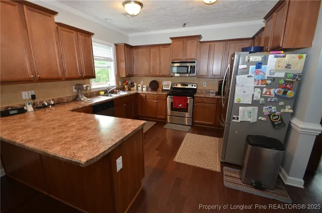 a kitchen with stainless steel appliances a refrigerator a sink a stove a microwave and wooden cabinets