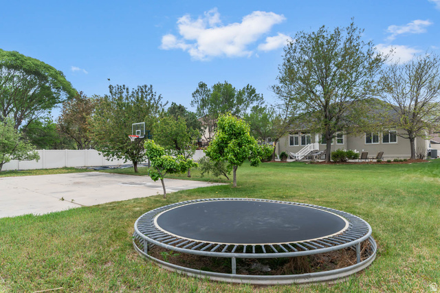 439 East 13540 South Draper, UT 84020 - Photo 43 of 46 Expansive backyard featuring a lush lawn, mature trees, concrete sports court with basketball hoop, and a vinyl privacy fence