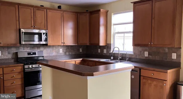 a kitchen with kitchen island granite countertop white cabinets sink and stainless steel appliances