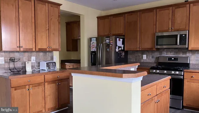 a kitchen with stainless steel appliances granite countertop a stove a sink dishwasher and a refrigerator with wooden cabinets