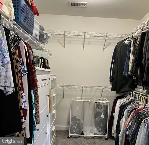 a view of walk in closet with clothes and shoes