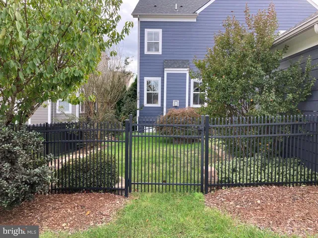 a view of a house in front of a yard with plants and large trees