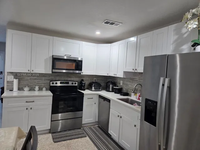 a kitchen with a sink a refrigerator and cabinets