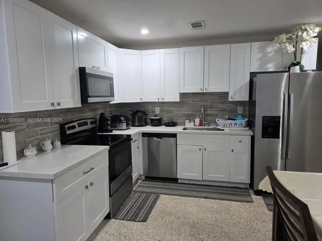 a kitchen with white cabinets sink and stainless steel appliances