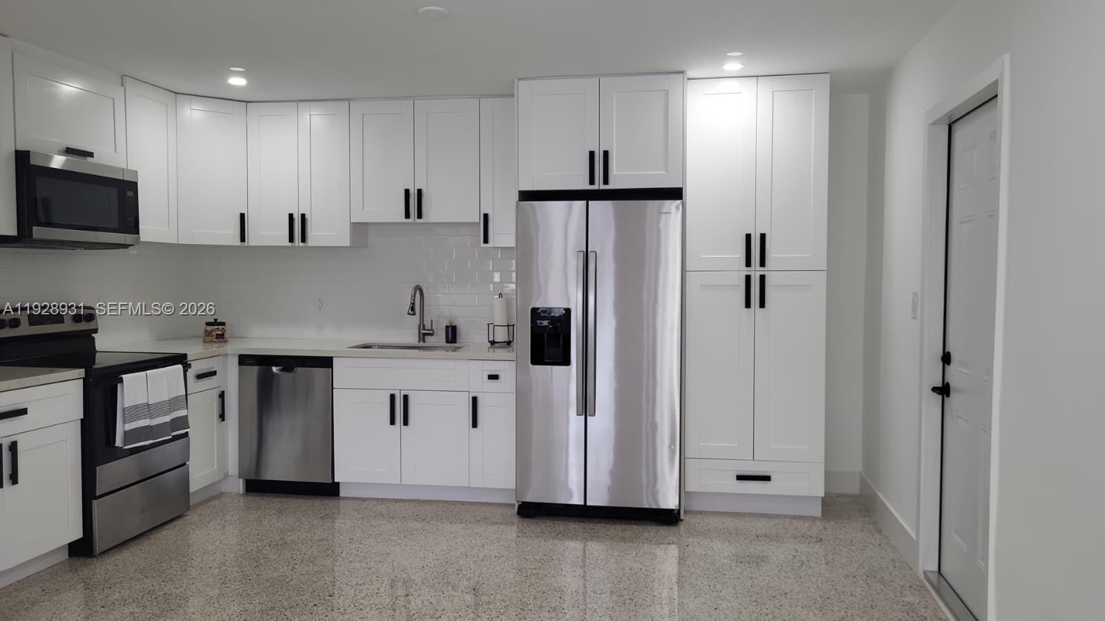 9228 Southwest 37th Street, Unit 9228 Miami, FL 33165 - Photo 5 of 27 a kitchen with stainless steel appliances a refrigerator sink and white cabinets