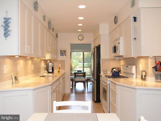 2023 Sarazen Place Reston, VA 20191 - Photo 17 of 30 a kitchen with stainless steel appliances a sink a stove a refrigerator and cabinets