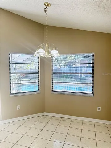 an empty room with chandelier fan and windows